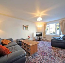 A living room with sofas coffee table television and a bookshelf at Mosslea in Bowness