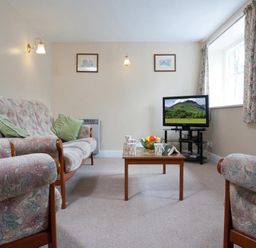 A living room with sofas a wooden coffee table and a television at Low Croft Cottage in Grasmere