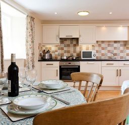 A kitchen with a dining table set with plates glasses and a wine bottle at Low Croft Cottage in Grasmere