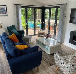 A living room with blue and patterned chairs a white coffee table and a wall-mounted tv at Windermere Lodge in Bowness-On-Windermere