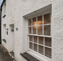 White textured exterior wall with a window and a door numbered 3 on a row of similar houses