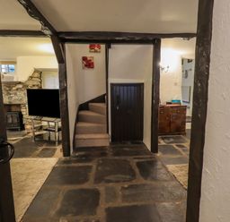 A hallway with a small staircase carpeted leading up and a small black door beneath the stairs at Birchcroft in Ambleside