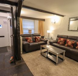 A living room with two leather sofas a glass coffee table and lamps at Birchcroft in Ambleside