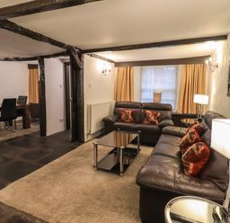 A living room with two leather sofas a glass coffee table and a dining area with a table and chairs at Birchcroft in Ambleside