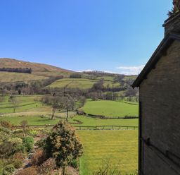 A garden and fields with trees and hills under a clear sky at Boxwood Cottage in Troutbeck