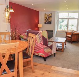 A living room with a dining table and chairs along with a sofa and armchair at Boxwood Cottage in Troutbeck
