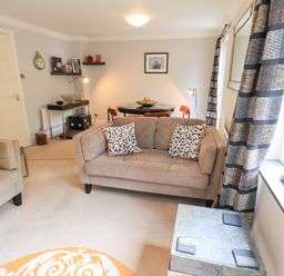 A living room with sofas, a dining table, and shelves at Ghyll Heights in Ambleside