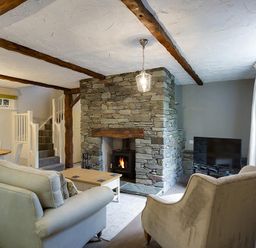 A living room with sofas a stone fireplace and a TV at Acorn Cottage in Grasmere
