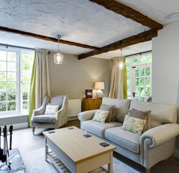 A living room with a sofa a chair a coffee table and large windows at Acorn Cottage in Grasmere