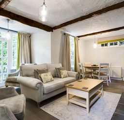 A living room with a sofa armchairs coffee table dining table and chairs at Acorn Cottage in Grasmere