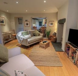 A living room with two sofas a wooden crate coffee table a television on wooden crates and an open doorway leading to a kitchen at Wainwright Cottage in Ambleside