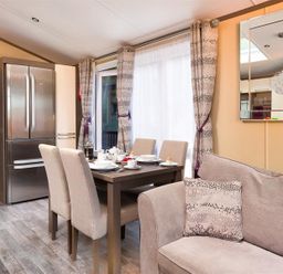 A dining area with a table set for breakfast next to a sofa and a refrigerator in a living space at Lancashire Rose Ambleside