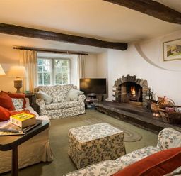 A living room with sofas and an armchair around a fireplace at High Cleabarrow in Windermere