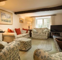 A living room with sofas and a television by a window at High Cleabarrow in Windermere