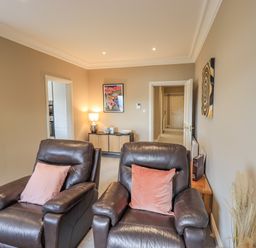A living room with two leather armchairs and a sideboard with a lamp and artwork at Waterhead Retreat in Ambleside