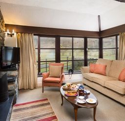 A living room with a sofa armchair coffee table and window at Thirlmere Cottage in Grasmere