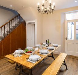 A dining room with a wooden table set for six and a wooden bench near stairs and a door at Thirty Blencathra Street Keswick