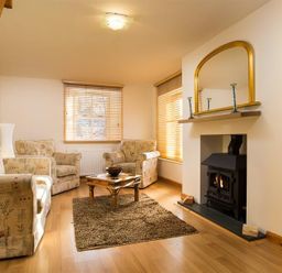A living room with armchairs a coffee table and a fireplace at Agathi in Keswick