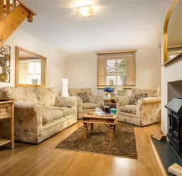 A sitting room with patterned sofas a wooden coffee table a small rug and a fireplace at Agathi in Keswick