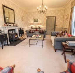 A living room with gray sofas and plaid cushions a fireplace and armchairs at Stepping Stones House in Ambleside