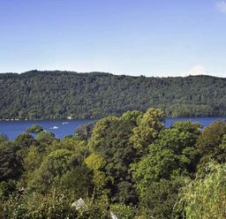 A landscape with trees in the foreground a lake and hills in the background at Primrose Mount in Bowness
