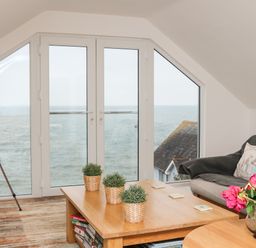 A sitting area with a telescope near glass doors overlooking the sea at St Julien in Dawlish