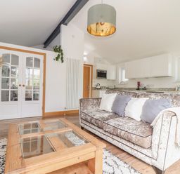 A living room with a sofa and coffee table near a kitchen at Chycoose in Hicks Mill near Perranarworthal