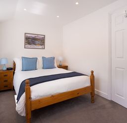 A bedroom with a wooden bed blue pillows bedside tables and lamps at Fern Cottage Ambleside