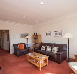A living room with brown leather sofas a wooden coffee table bookshelf and floor lamps at Romney 12 Waterhead near Ambleside