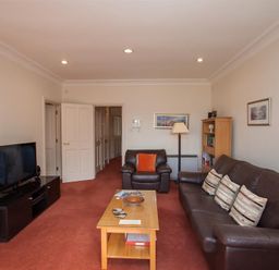 A living room with leather sofas a coffee table a television and a bookshelf at Romney 12 Waterhead near Ambleside