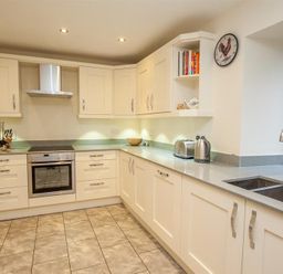 A kitchen with cream cabinets stainless steel appliances a double sink and a window at The Miller in Ambleside