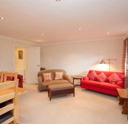 A living room with a red sofa wooden chairs and a television at The Miller in Ambleside