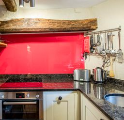 A kitchen with electric stove oven knife block toaster kettle and hanging utensils at Knotts Cottage in Troutbeck