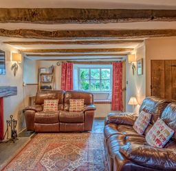 A living room with leather sofas and a fireplace at Knotts Cottage in Troutbeck