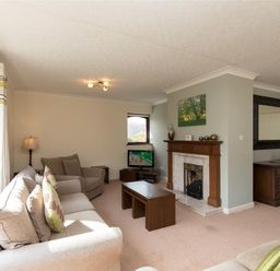 A living room with sofas a fireplace a television and a wooden cabinet at Todd Crag in Ambleside