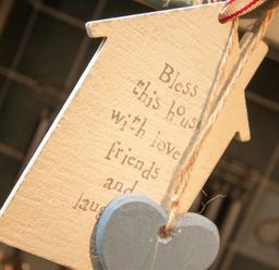 A wooden house-shaped decoration with text and a hanging gray heart at Sunset Cottage in Ambleside