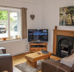 A living room with leather sofas a wooden coffee table television and a fireplace at Four Seasons Cottage in Ambleside