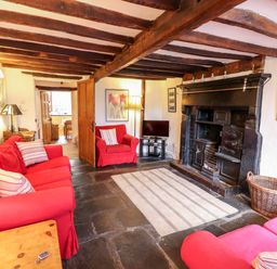 A living room with red sofas a rug and a large black fireplace at Rock Cottage in Ambleside
