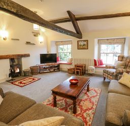 A living room with sofas a coffee table a fireplace and windows with cushions at Highfold Ambleside