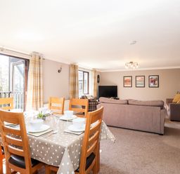 A dining table set with six chairs and bowls in a living room with sofas and a TV at Ghyll View in Ambleside