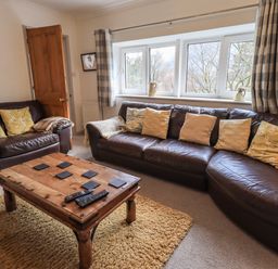 A living room with brown leather sofas and a wooden coffee table at Rawfell in Great Langdale