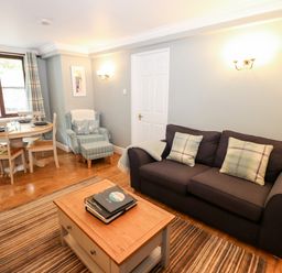 A living room with a sofa, armchair, coffee table, dining table and chairs at Babbling Brook in Ambleside