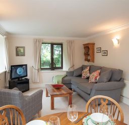 A living room with a gray sofa and armchair a wooden coffee table and a television at Over Ghyll in Ambleside