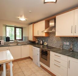 A kitchen with white cabinets a green countertop tiled floor and a window at Over Ghyll in Ambleside