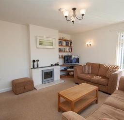 A living room with brown sofas a wooden coffee table a fireplace and a television at Bield How in Ambleside
