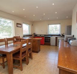 A kitchen with wooden dining table and chairs red stove and appliances at Bield How in Ambleside