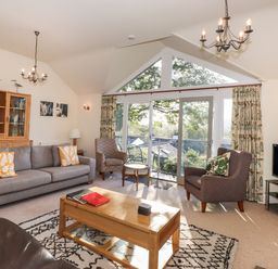 A living room with sofas armchairs a coffee table and a television at Garden House in Ambleside