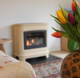 A vase with colorful tulips in front of a fireplace and a couch at Bank Foot in Ambleside