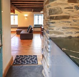 An open doorway showing a living room with a brown couch wooden floor stone wall and a countertop at Janes Cottage in Hawkshead
