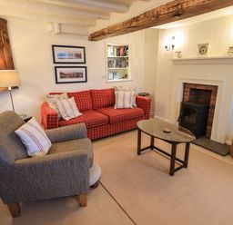 A living room with a fireplace two sofas a wooden coffee table and framed pictures at Nurses Cottage in Hawkshead